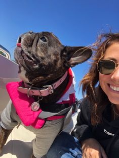 a woman sitting next to a dog wearing sunglasses