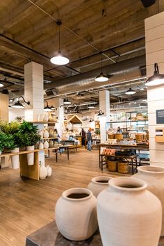 the interior of a pottery store with large vases and tables full of plants on display