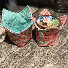 two small containers with food inside sitting on a counter next to another container that has something in it