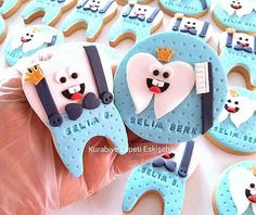 decorated cookies in the shape of letters with faces and crowns are being held by someone's hand