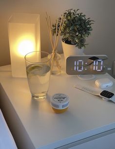 an alarm clock sitting on top of a white table next to a glass filled with water