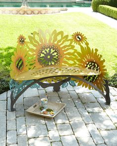 a bench with sunflowers painted on it in the middle of a garden area