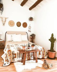 a bed room with a neatly made bed next to a cactus and potted plants