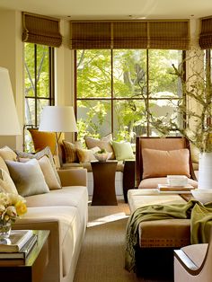 a living room filled with lots of furniture next to a large window covered in curtains