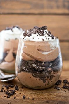 two desserts in glass jars with spoon on wooden table