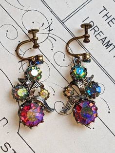 Here we have a beautiful 1940's pair of Delissa Juliana Screw back earrings, featuring stunning aurora borealis rainbow Crystals. The screw backs seem to be in an aged gold toned metal and the backs of the earrings in a silver toned metal. There seems to be a slight patina and tarnish to them, however they are still absolutely beautiful.  Why not give the gift of history... Like a time capsule as a gift. ~FREE DELIVERY~ If you have any questions, queries, or want to know more about shipping else Vintage Dangle Clip-on Earrings For Gift, Vintage Silver Crystal Earrings For Pierced Ears, Vintage Nickel-free Crystal Earrings For Gift, Vintage Crystal Drop Earrings For Pierced Ears, Vintage Dangle Crystal Earrings For Gift, Vintage Dangle Crystal Earrings As Gift, Vintage Clip-on Drop Earrings, Vintage Multicolor Round Clip-on Earrings, Victorian Drop Earrings For Vintage Events