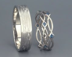 two wedding bands with blue sapphire stones in the center and an intricate design on each band