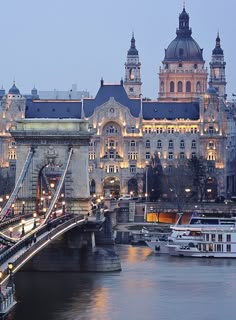 a large building next to a river with boats in the water and lights on it