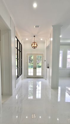 an empty hallway with two doors leading to another room in the background and light fixtures on either side