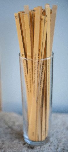 a glass filled with wooden sticks sitting on top of a table