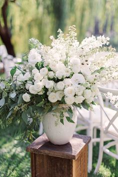 a white vase filled with flowers sitting on top of a wooden block