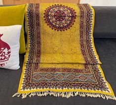 a yellow blanket sitting on top of a couch next to pillows