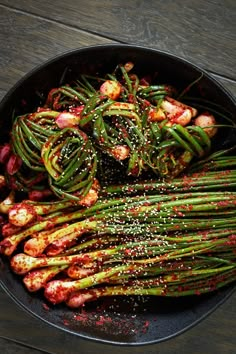 asparagus with sesame seeds and seasoning in a skillet on a wooden table