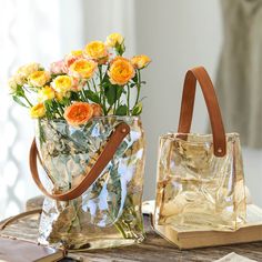 two clear bags with flowers in them sitting on a wooden table next to each other