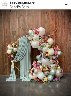 balloons and flowers are on display in front of a wooden wall