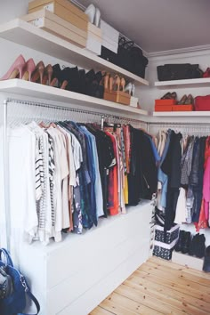 a closet filled with lots of clothes and handbags on shelves next to wooden flooring