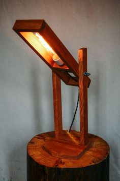 a wooden table lamp on top of a tree stump with a light bulb in the middle