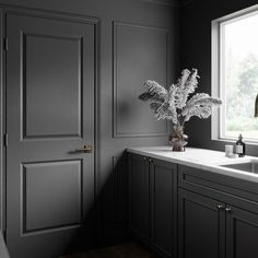 A gray two-panel door with gray walls and wainscoting, a marble utilty sink and large picture window Classic Laundry Room