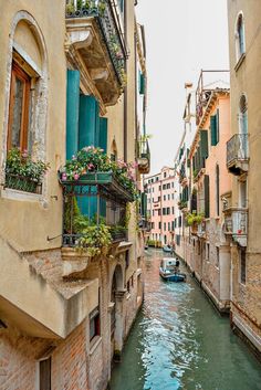 a narrow canal runs between two buildings with balconies and flowers on the balcony