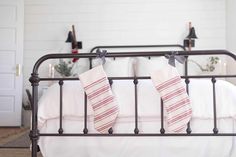 two christmas stockings are hanging on the iron bed frame in this white and red bedroom