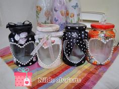 four jars are decorated with flowers and pearls