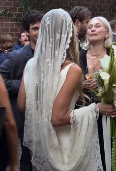 a woman in a wedding dress and veil standing next to a man wearing a suit