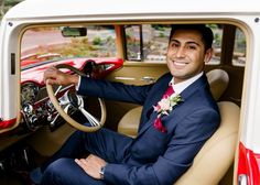 a man in a suit and tie sitting in the driver's seat of a car