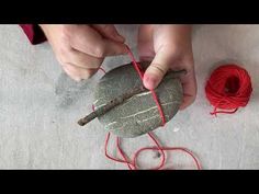 someone is making something out of rock and yarn