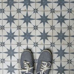 someone's shoes are standing on the floor in front of a star pattern tile