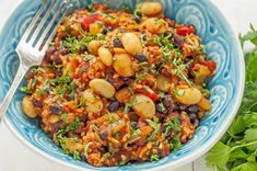 a blue and white bowl filled with beans, rice and cilantro sauce next to some parsley