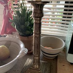 a candle is sitting on top of a table next to two bowls and a potted plant