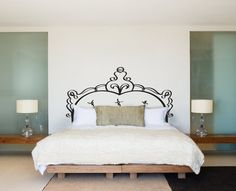 a white bed sitting next to two lamps on top of a wooden table in a bedroom