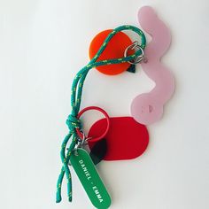 two key chains with tags attached to them on a white surface, one is red and the other is green