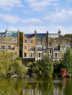 some buildings are next to a body of water with trees in the foreground and bushes on either side