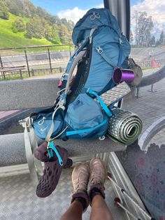 a person's feet resting on the back of a bus with backpacks and yoga mats