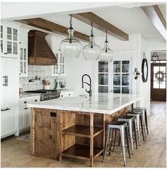 a kitchen with white cabinets and marble counter tops in the center is surrounded by stools