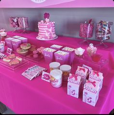 a pink table topped with lots of desserts and candy bar items on top of it