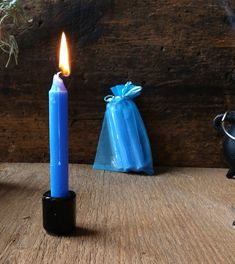 a blue candle sitting on top of a wooden table next to a teapot and pot