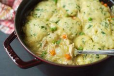 a pot filled with dumplings and vegetables on top of a table