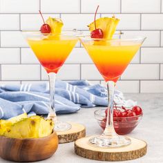 two cocktails with pineapple garnish and cherries