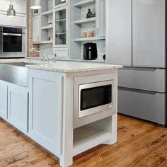 a kitchen with white cabinets and an island in the middle is shown, along with stainless steel appliances