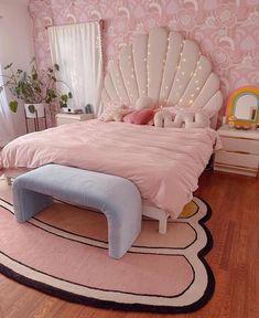 a pink and white bedroom with a large bed in the middle, an area rug on the floor