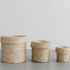 three round baskets sitting next to each other on top of a cement floor with white walls in the background