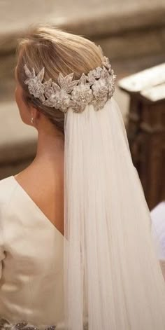 the back of a bride's head wearing a veil with flowers and pearls on it