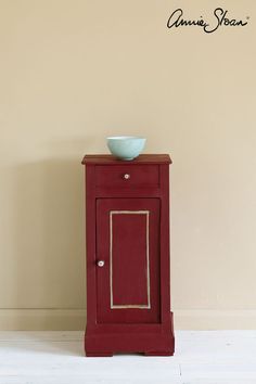 a small red cabinet with a bowl on top