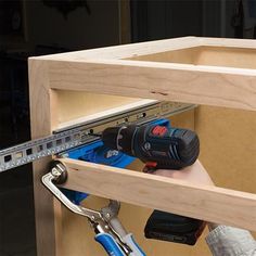 a man is holding a drill and tool in his hand as he works on some wood