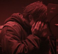 a man covering his face while standing in front of a microphone