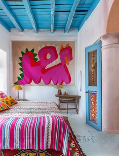 a bedroom decorated in bright colors with a large painting on the wall