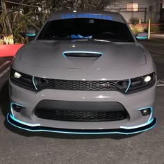 the front end of a gray car with blue lights