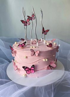 a pink cake decorated with butterflies and candles